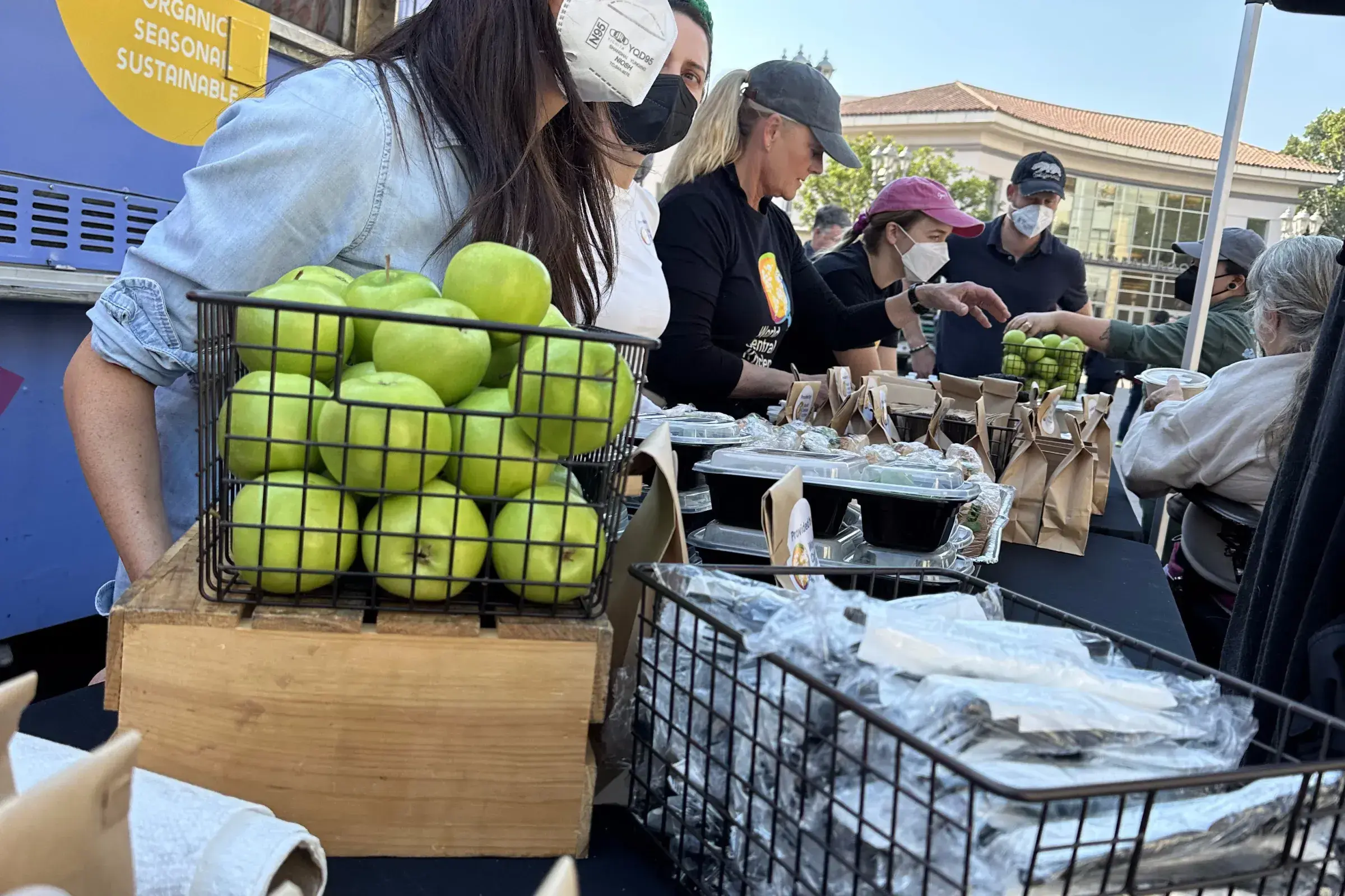 An image of Meghan Markle serving green apples and food to civilians 
