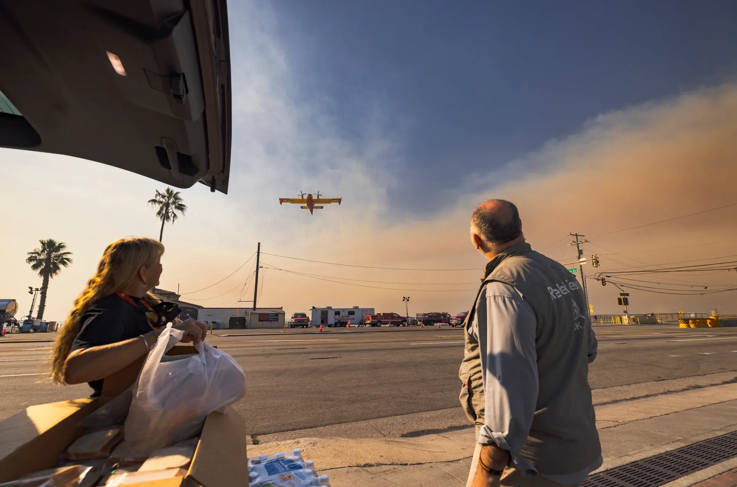 An image of José Andrés and a relief worker looking at a relief plane in the sky